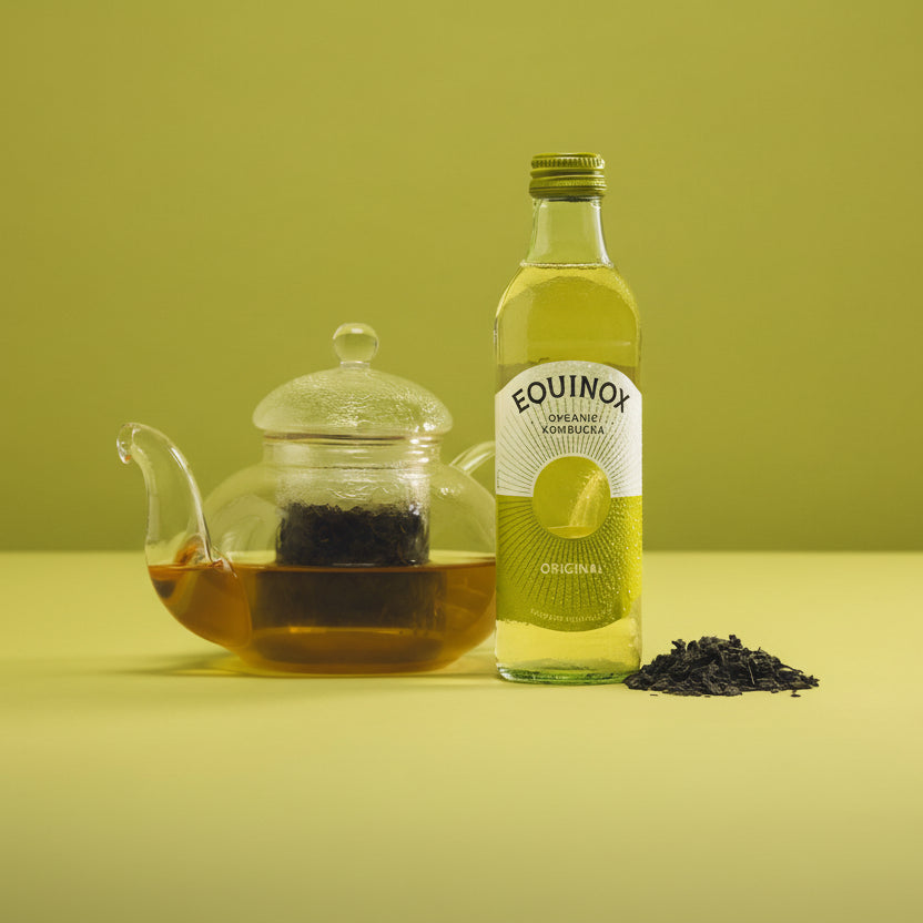 Bottle of Equinox Organic Kombucha with a teapot and tea leaves on a yellow background